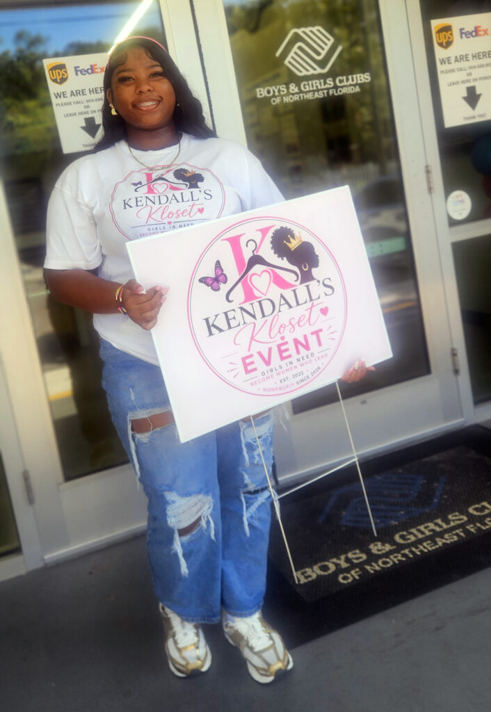 Kendall holding an event sign at a store.